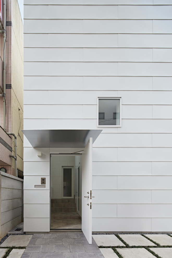 Inspiration pour une façade de maison métallique et blanche design à niveaux décalés avec un toit plat.