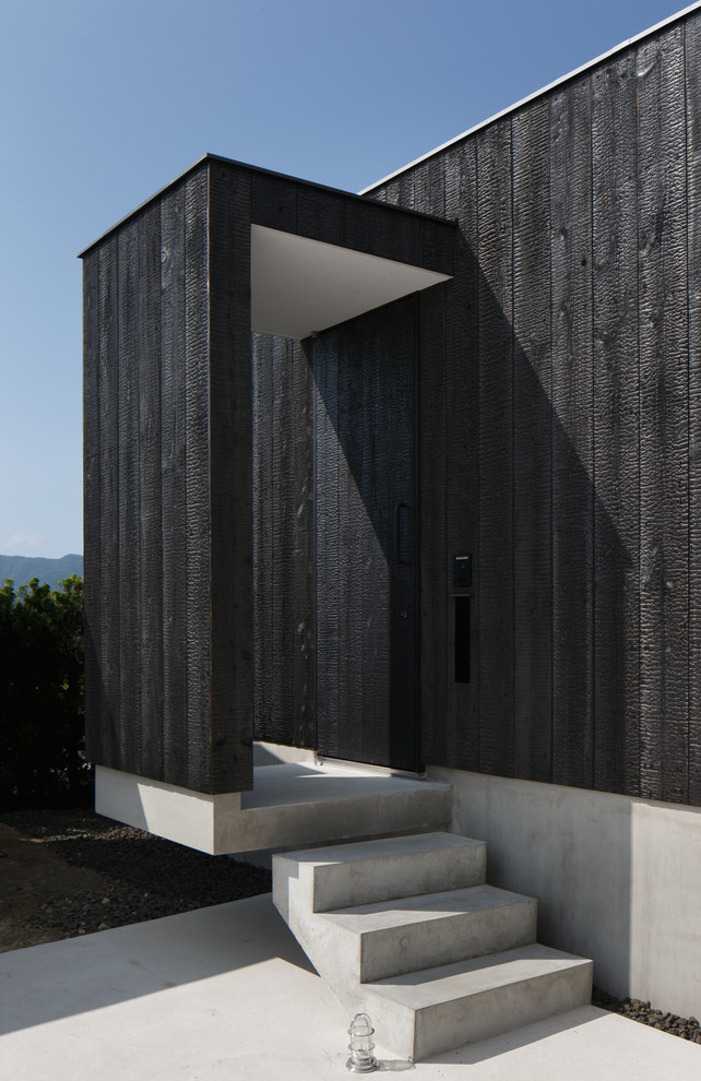 This is an example of a black house exterior in Other with wood cladding.