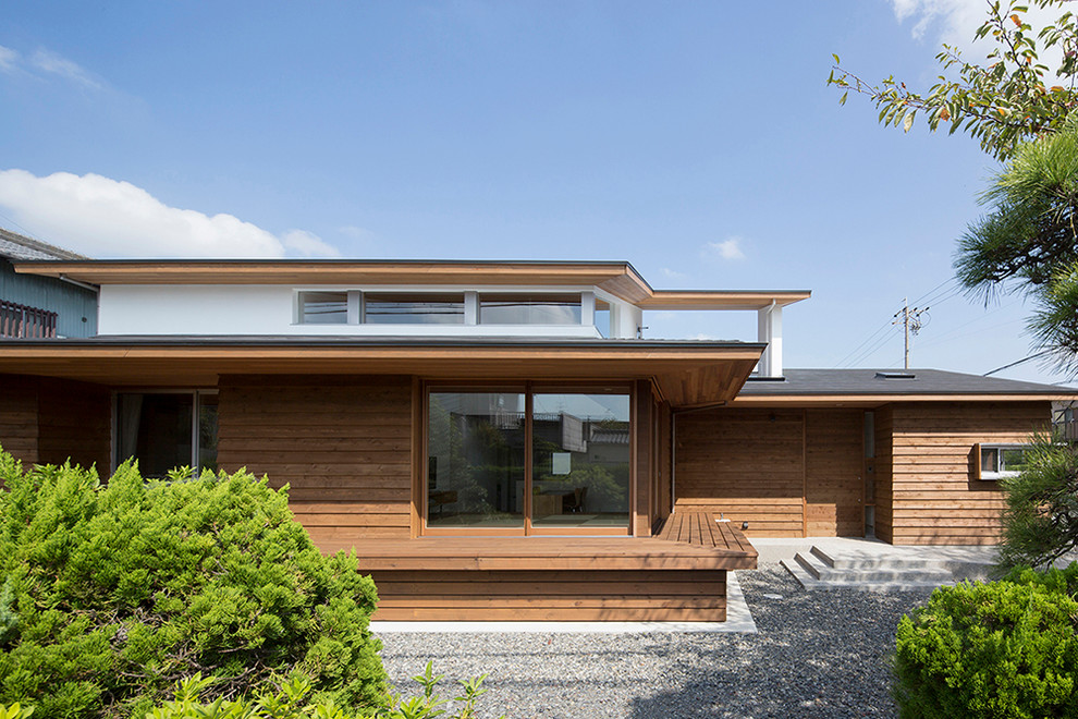 Пример оригинального дизайна: деревянный, коричневый, двухэтажный частный загородный дом в японском стиле, среднего размера в классическом стиле с односкатной крышей, металлической крышей, серой крышей и отделкой планкеном