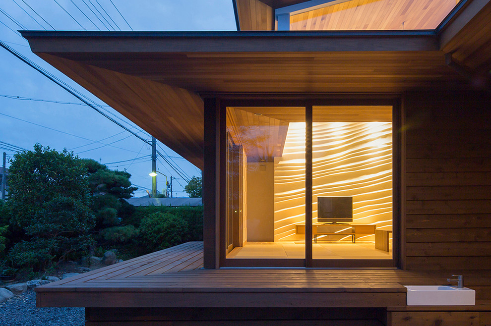 На фото: деревянный, коричневый, двухэтажный частный загородный дом в японском стиле, среднего размера в современном стиле с односкатной крышей, металлической крышей, серой крышей и отделкой планкеном с