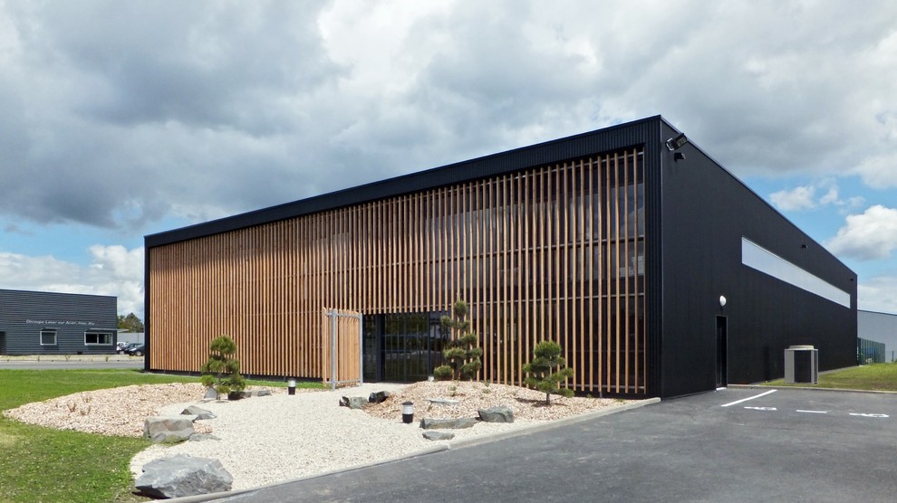 Réalisation d'une façade de maison noire design en bois à un étage avec un toit plat.
