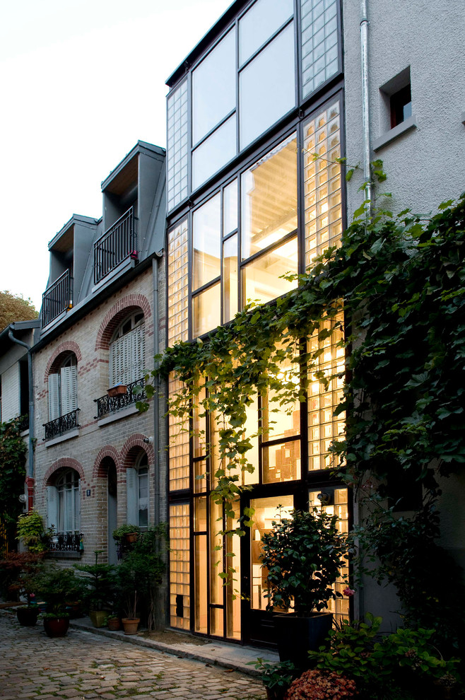 Diseño de fachada de casa pareada gris contemporánea de tres plantas con revestimiento de vidrio y tejado plano