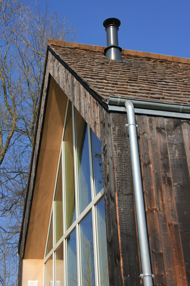 Small and black contemporary house exterior in Le Havre with three floors, wood cladding and a pitched roof.