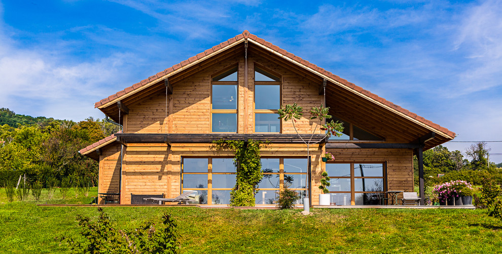 Réalisation d'une grande façade de maison marron chalet en bois à un étage avec un toit à deux pans.