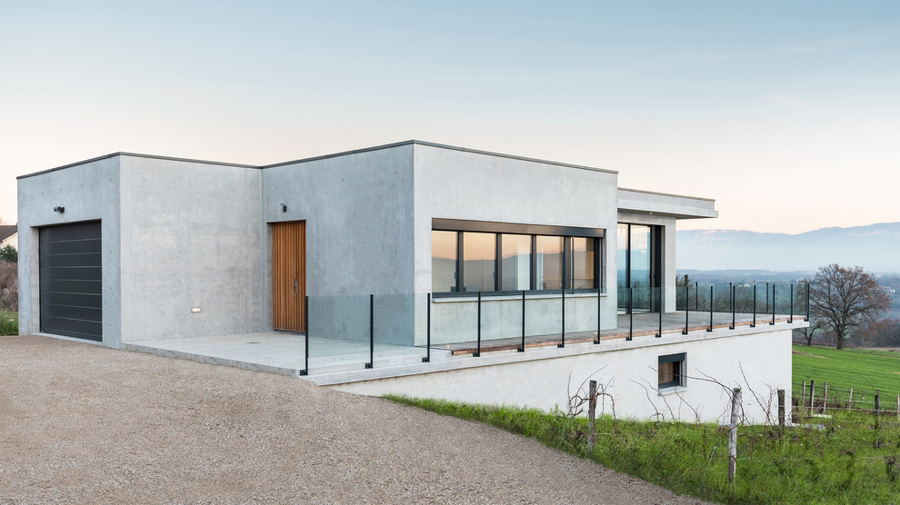 На фото: серый дом среднего размера в стиле модернизм с плоской крышей и облицовкой из бетона