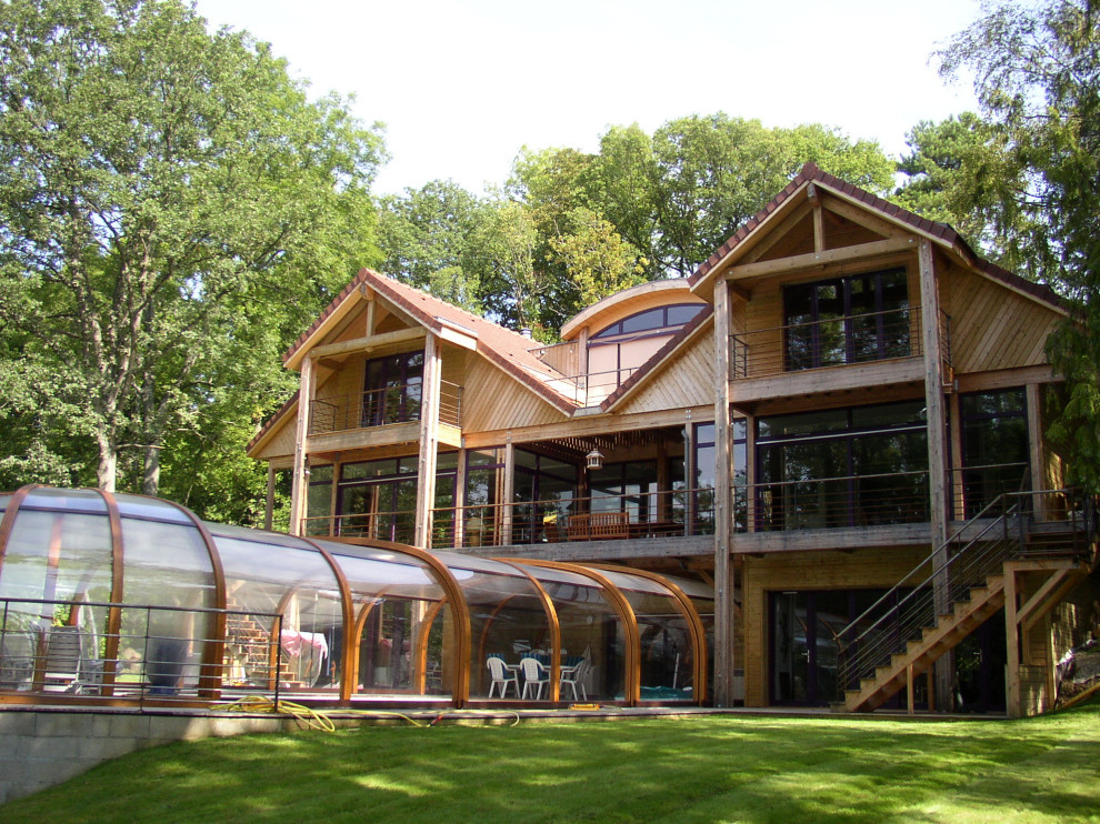 Réalisation d'une grande façade de maison marron design en bois et bardage à clin à deux étages et plus avec un toit à deux pans, un toit en tuile et un toit rouge.