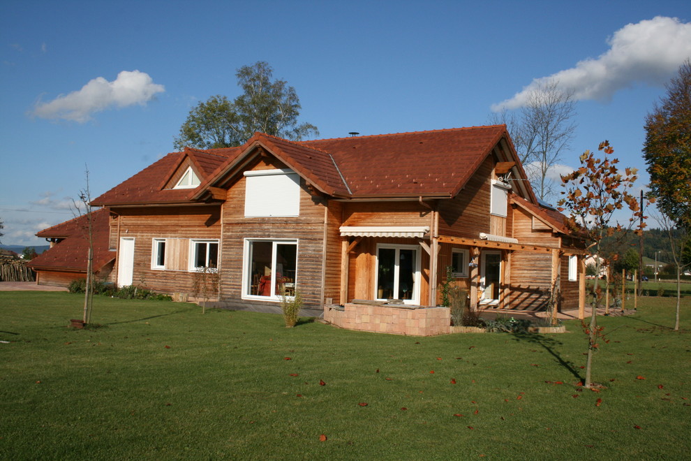 Пример оригинального дизайна: большой, двухэтажный, деревянный, бежевый частный загородный дом в стиле рустика с мансардной крышей и черепичной крышей