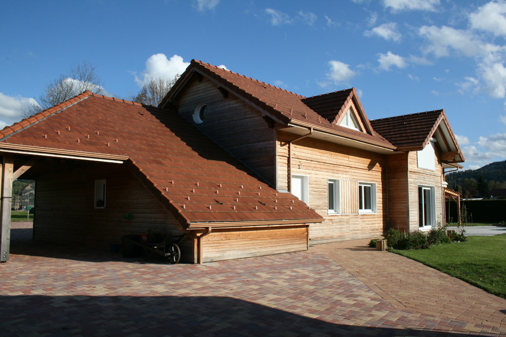 Inredning av ett rustikt stort beige hus, med två våningar, mansardtak och tak med takplattor