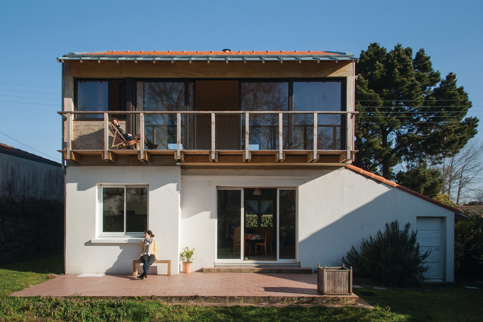 Cette image montre une façade de maison beige design à un étage avec un toit à deux pans.