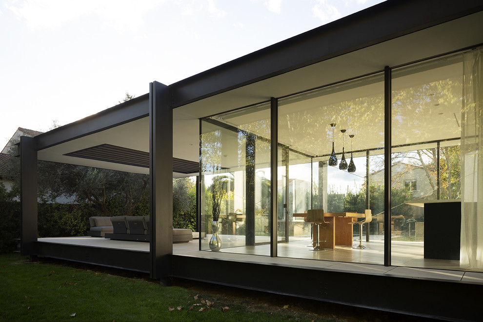 Réalisation d'une façade de maison métallique et noire minimaliste de taille moyenne et à un étage avec un toit plat.