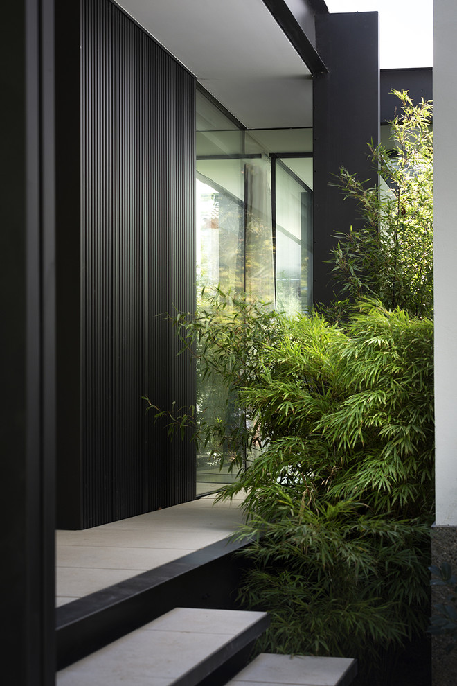 Modelo de fachada de casa negra minimalista de tamaño medio de dos plantas con revestimiento de metal y tejado plano