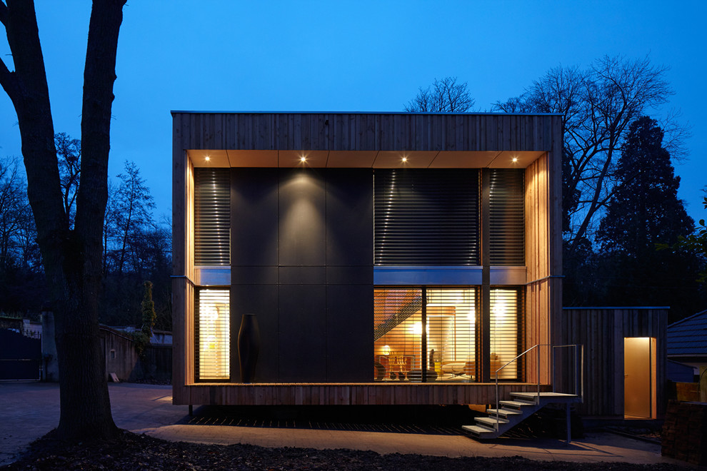 Ispirazione per la facciata di una casa nera contemporanea a due piani di medie dimensioni con rivestimento in vetro e tetto piano