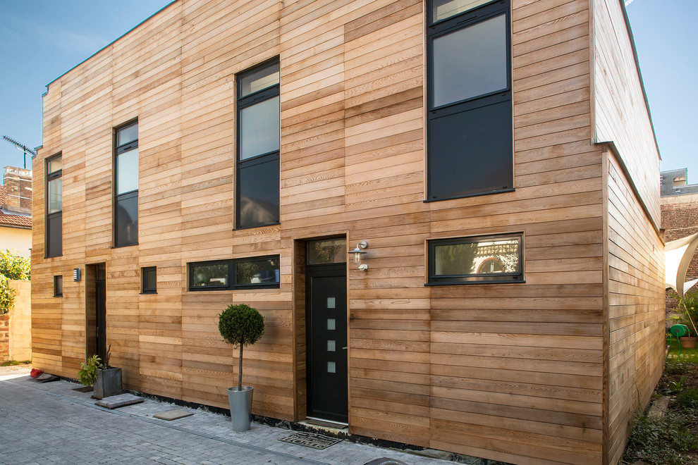Aménagement d'une façade de maison marron contemporaine en bois de taille moyenne et à un étage avec un toit plat.