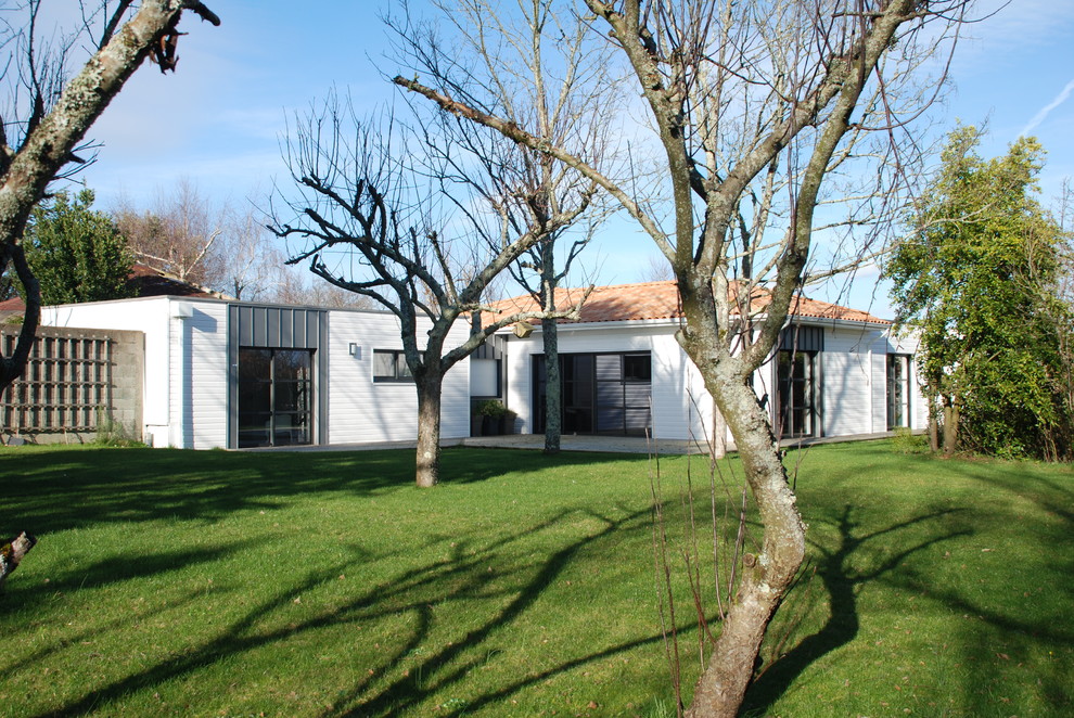Cette photo montre une façade de maison blanche tendance en bois de plain-pied avec un toit à quatre pans.