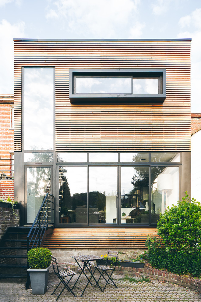Inspiration pour une façade de maison marron design en bois de taille moyenne et à un étage avec un toit plat.