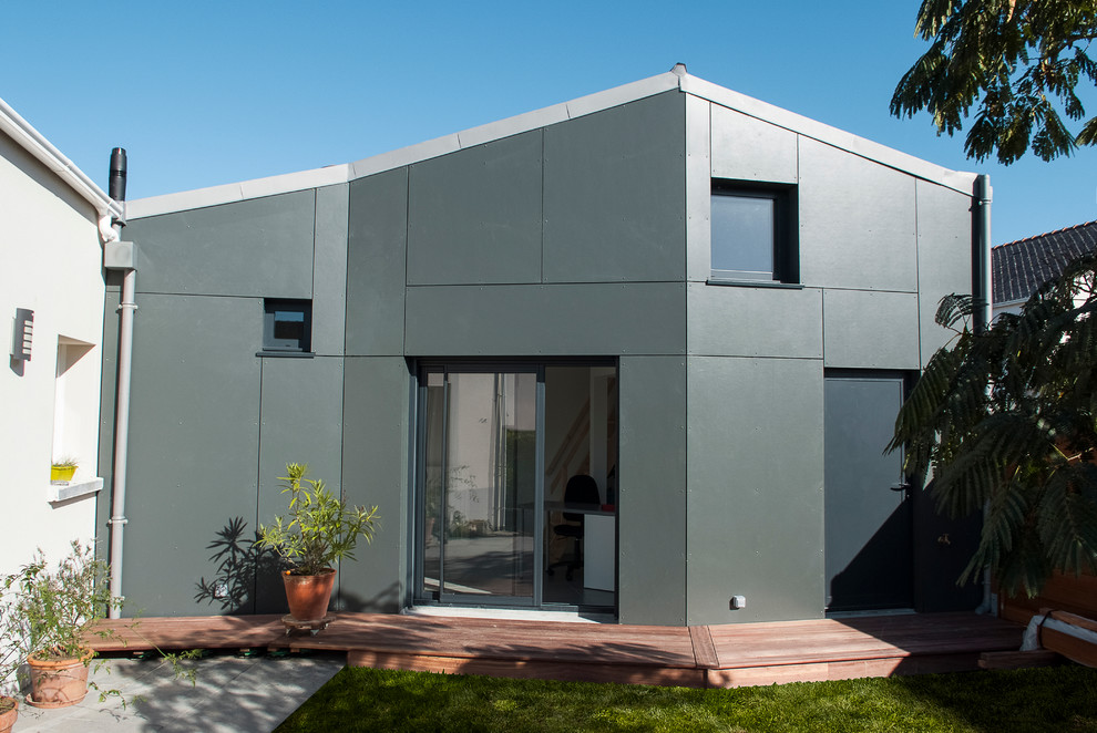 Imagen de fachada gris actual de tamaño medio de dos plantas con revestimiento de metal y tejado a dos aguas