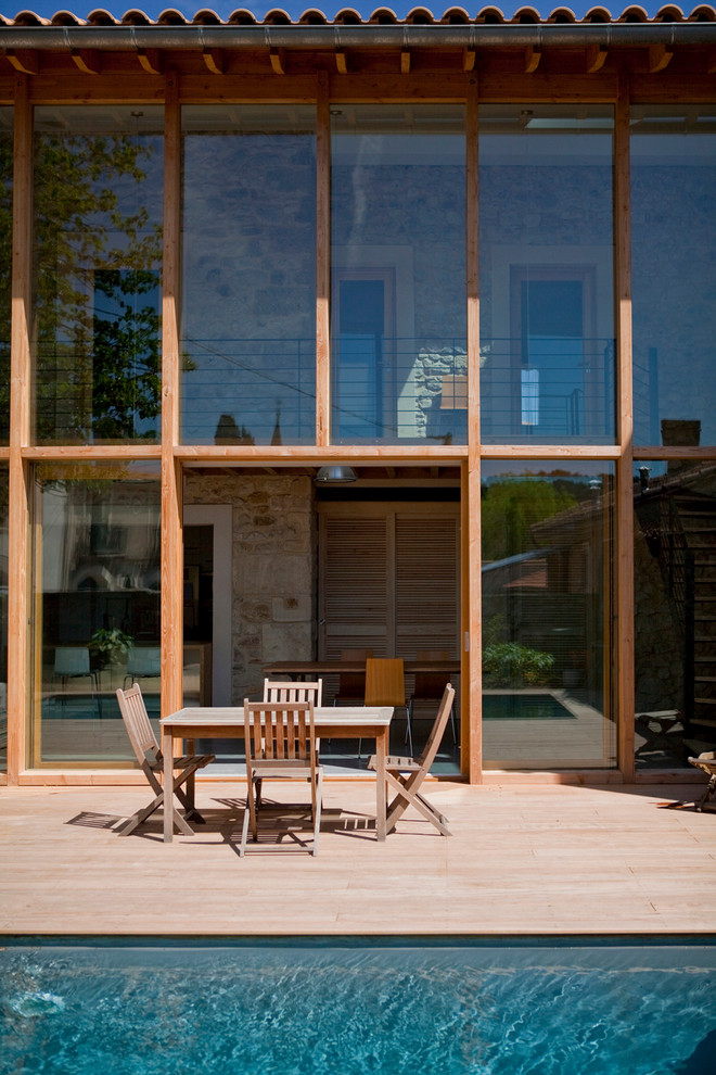 Modelo de fachada marrón contemporánea de tamaño medio de dos plantas con revestimiento de vidrio y tejado a dos aguas