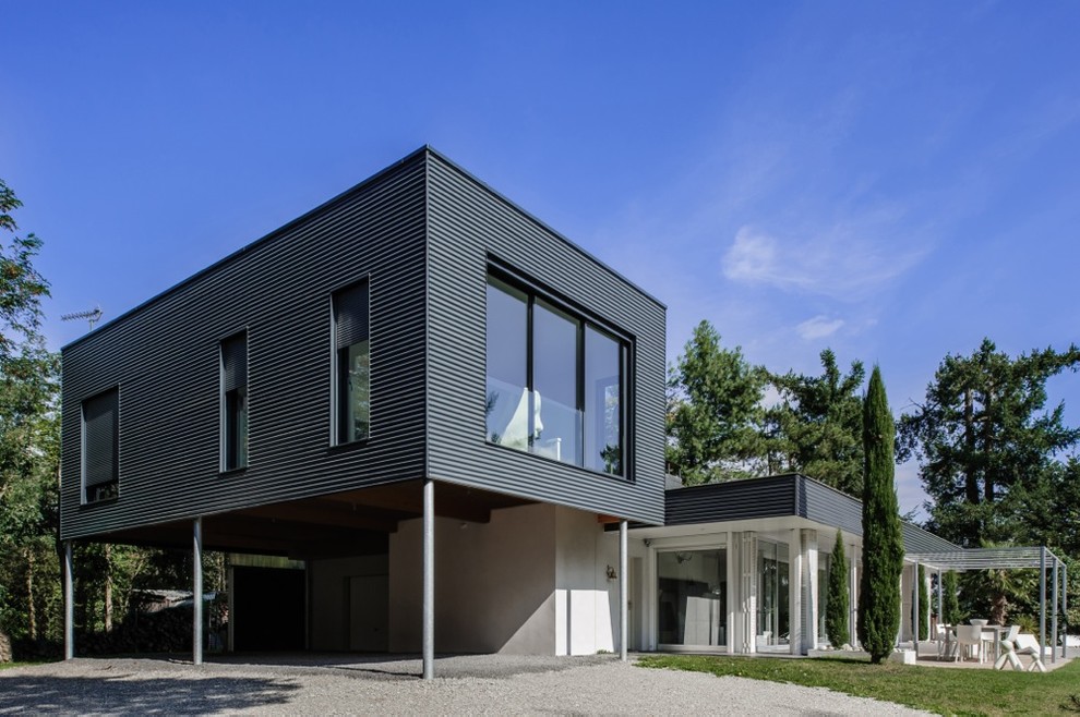 Стильный дизайн: двухэтажный, черный дом среднего размера в современном стиле с плоской крышей и облицовкой из металла - последний тренд