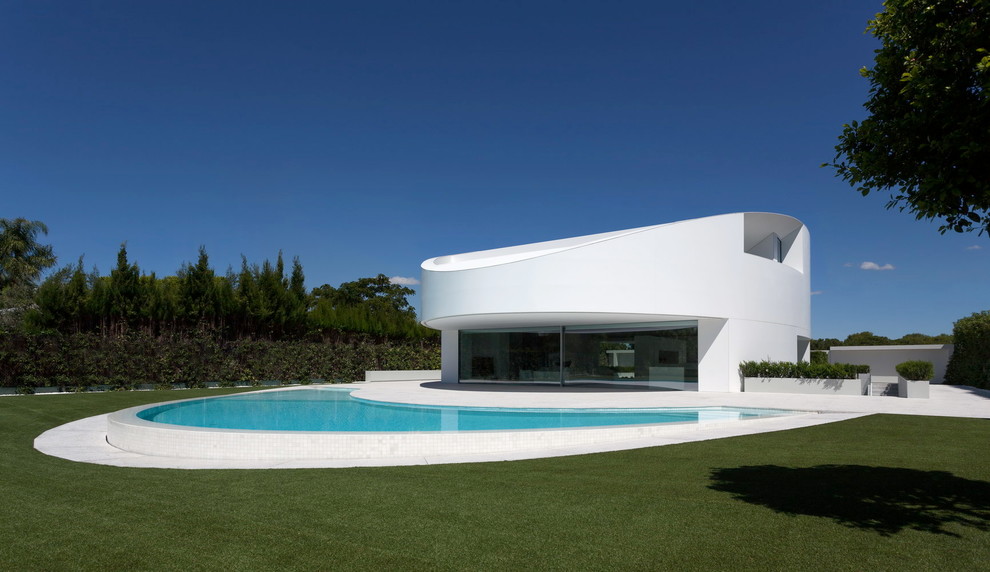 Réalisation d'une grande façade de maison blanche design à un étage avec un toit plat.