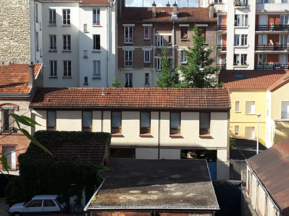 Modelo de fachada beige actual grande de tres plantas con revestimiento de estuco y tejado a dos aguas