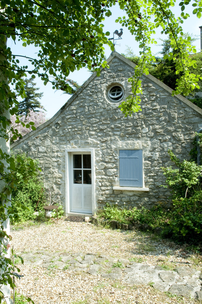 Example of a small farmhouse beige two-story stone gable roof design in Paris