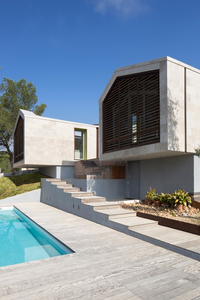 Medium sized and beige contemporary two floor house exterior in Montpellier with stone cladding and a pitched roof.