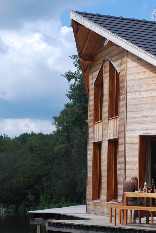 Cette image montre une façade de maison marron design en bois de taille moyenne et à un étage avec un toit à deux pans.