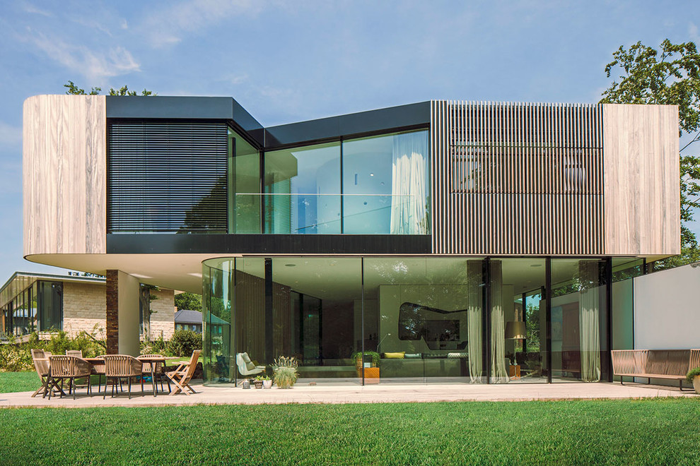 Imagen de fachada de casa negra moderna de dos plantas con revestimientos combinados y tejado plano