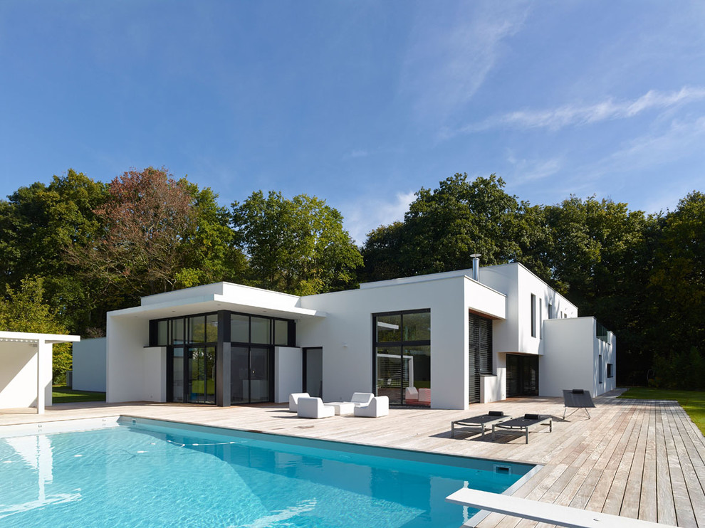 На фото: одноэтажный, белый дом в современном стиле с облицовкой из цементной штукатурки и плоской крышей