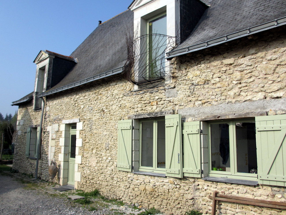 This is an example of a medium sized and beige contemporary two floor house exterior in Angers with stone cladding and a pitched roof.