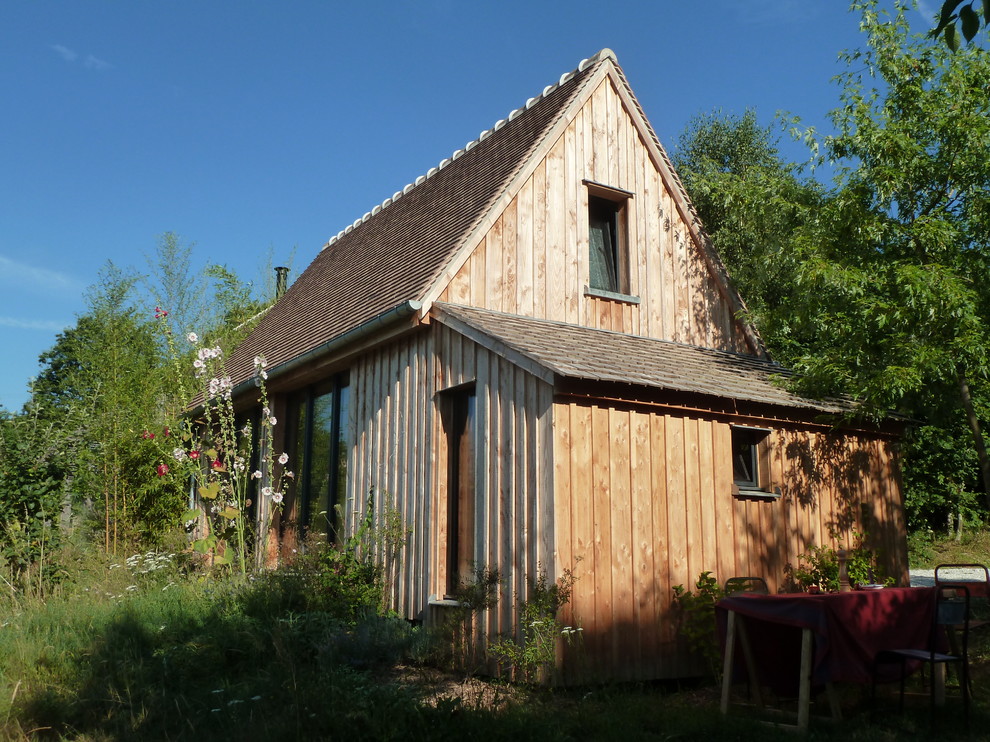 Esempio della villa marrone country a due piani di medie dimensioni con rivestimento in legno, tetto a capanna e copertura in tegole