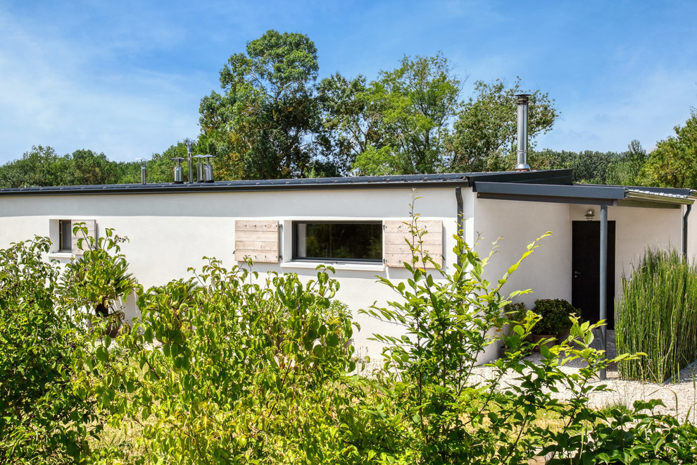 Large and white contemporary detached house in Toulouse with mixed cladding, a flat roof and a metal roof.