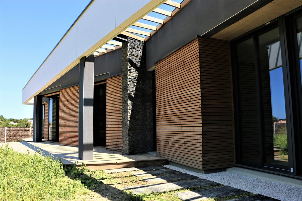 Cette image montre une façade de maison noire minimaliste en bois de taille moyenne et de plain-pied avec un toit plat.