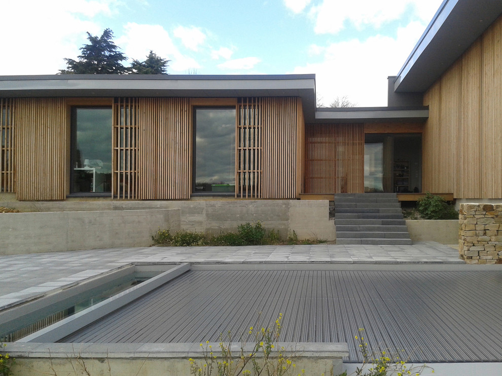 Immagine della villa grande marrone contemporanea a due piani con rivestimento in legno e tetto piano