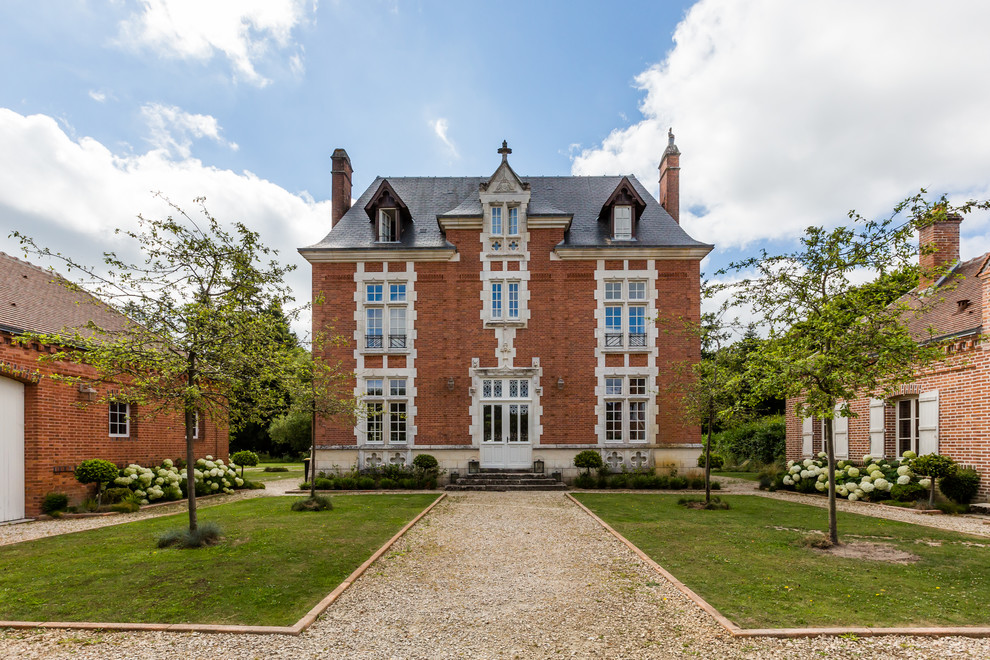Ornate three-story brick house exterior photo in Paris with a hip roof and a shingle roof