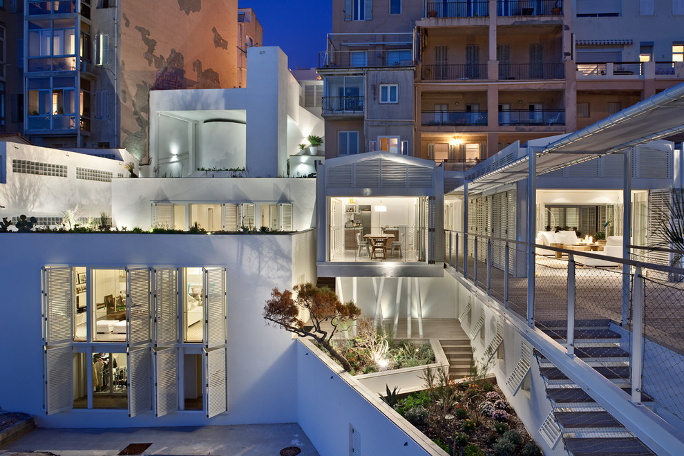 This is an example of a medium sized and white contemporary house exterior in Marseille with three floors and a flat roof.