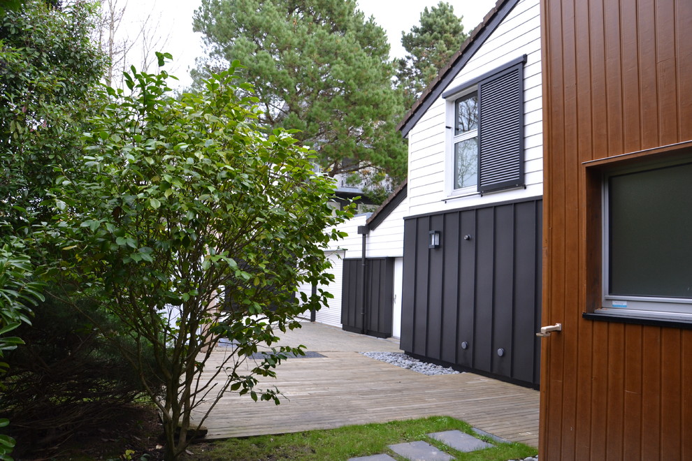This is an example of a medium sized and white modern two floor house exterior in Nantes with wood cladding.