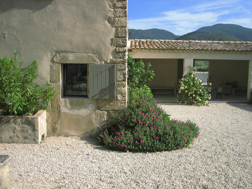 Aménagement d'une façade de maison beige méditerranéenne en pierre de taille moyenne et à un étage.