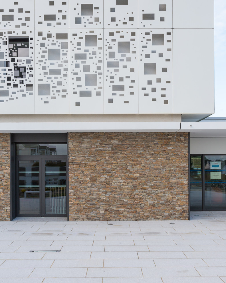 Ejemplo de fachada de piso multicolor contemporánea de tamaño medio de tres plantas con revestimiento de piedra