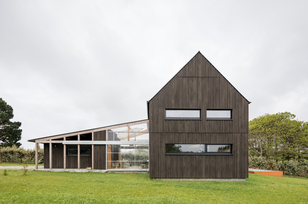 Foto della villa nera industriale a due piani di medie dimensioni con rivestimento in legno e tetto a capanna