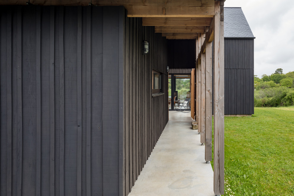 Exemple d'une façade de maison noire industrielle en bois de taille moyenne et à un étage avec un toit à deux pans.