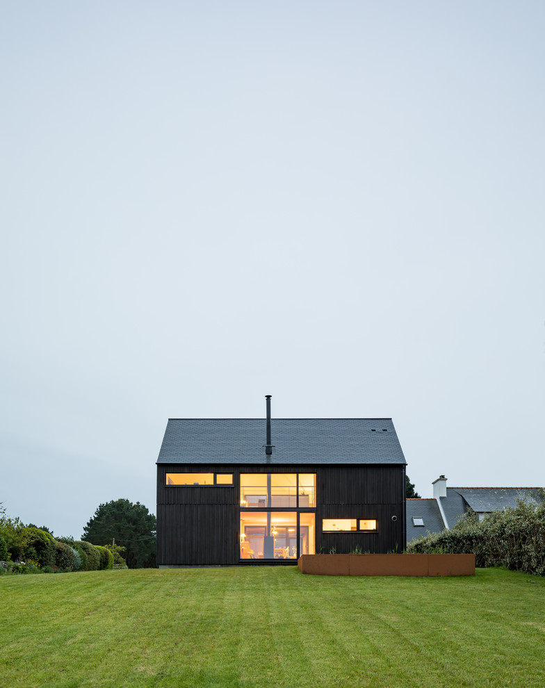 This is an example of a medium sized and black industrial two floor detached house in Other with wood cladding and a pitched roof.
