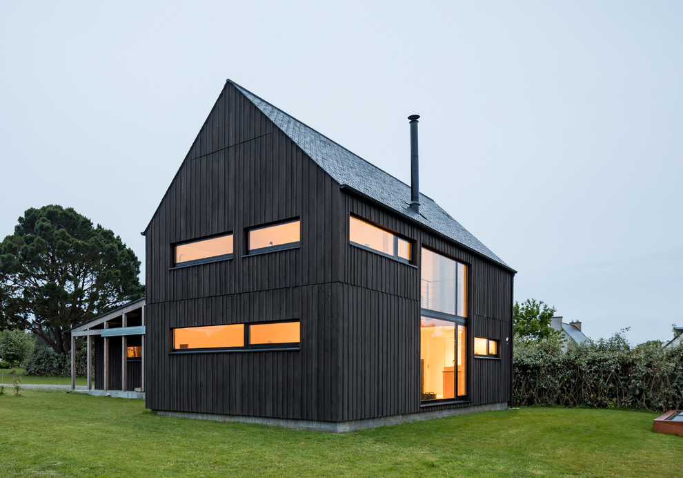 Cette image montre une façade de maison noire urbaine en bois de taille moyenne et à un étage avec un toit à deux pans.