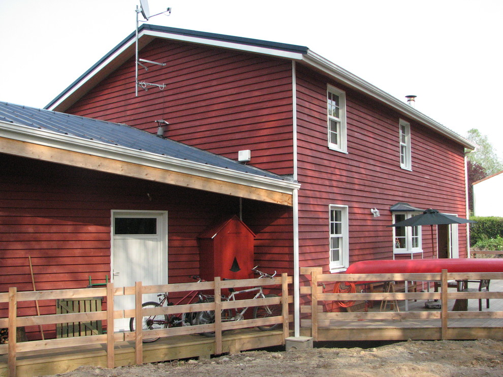 Réalisation d'une façade de maison rouge champêtre en bois de taille moyenne et à un étage avec un toit à deux pans et un toit en métal.