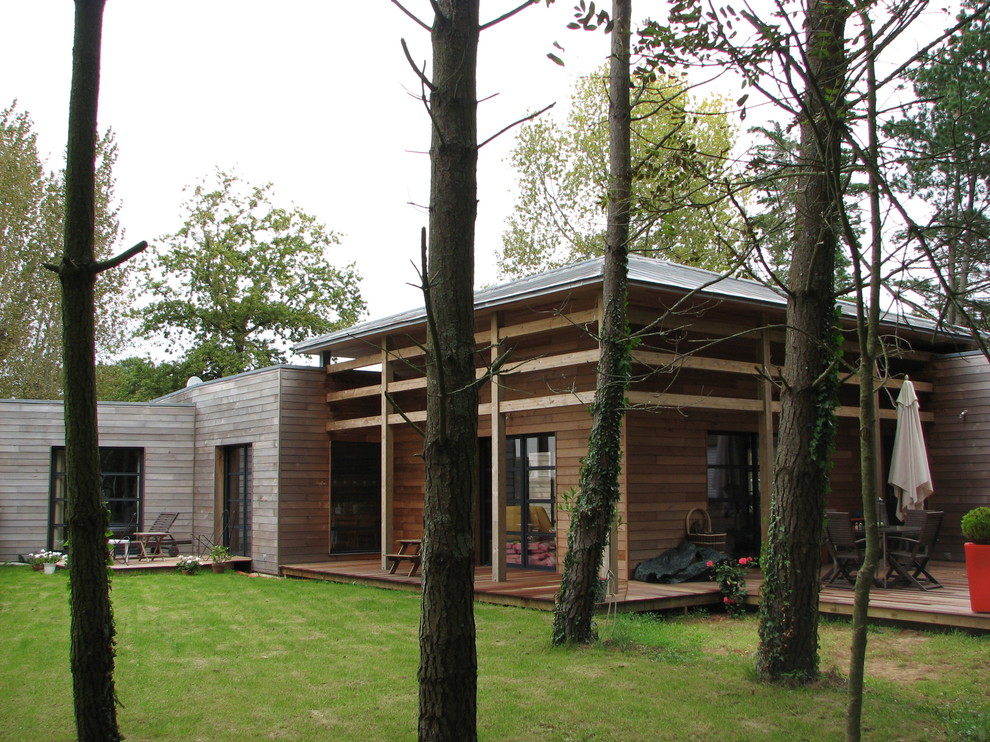 Inspiration pour une grande façade de maison marron design en bois de plain-pied avec un toit à quatre pans et un toit en métal.