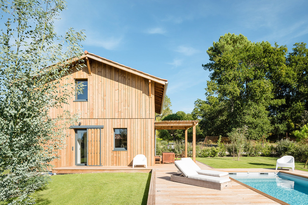Diseño de fachada de casa campestre de dos plantas con revestimiento de madera y tejado a dos aguas