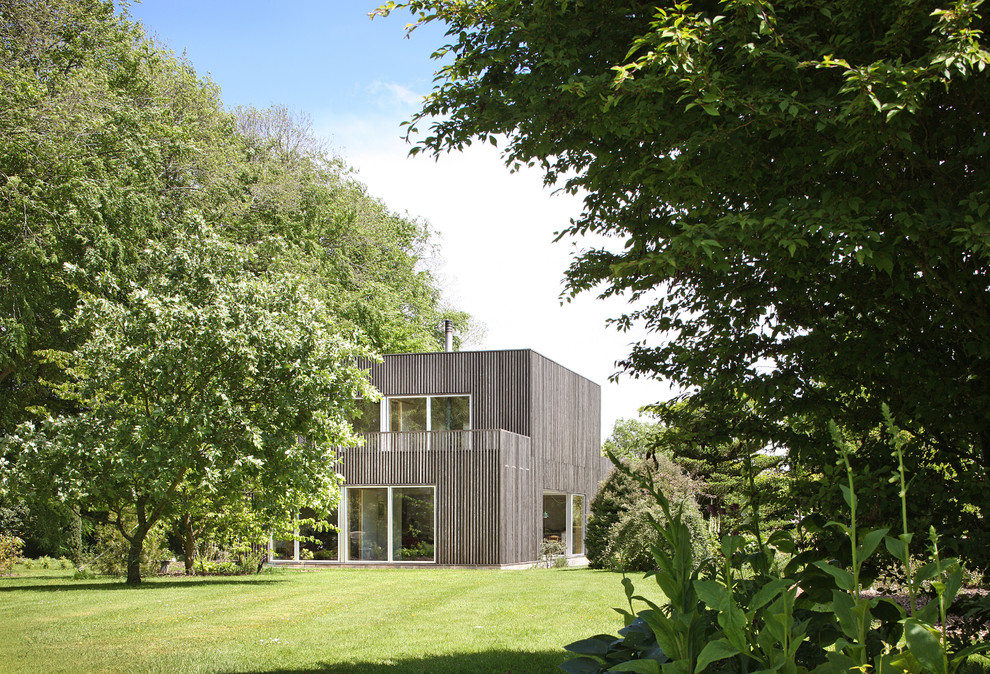На фото: двухэтажный, деревянный, коричневый дом в стиле модернизм с плоской крышей с