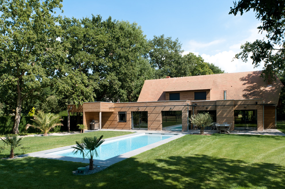 Ejemplo de fachada de casa marrón contemporánea de tamaño medio de dos plantas con revestimiento de madera, tejado plano y tejado de teja de barro