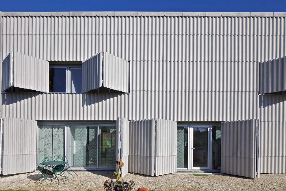 Diseño de fachada urbana grande de dos plantas con revestimiento de metal y tejado plano