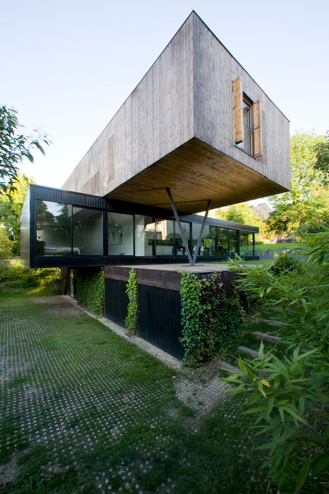 Réalisation d'une façade de maison container design en bois à deux étages et plus avec un toit plat.
